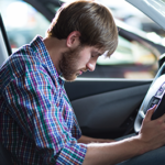 Male in his 20s sitting in the driver's seat of a vehicle waiting with his head down while his is being accused of a dui